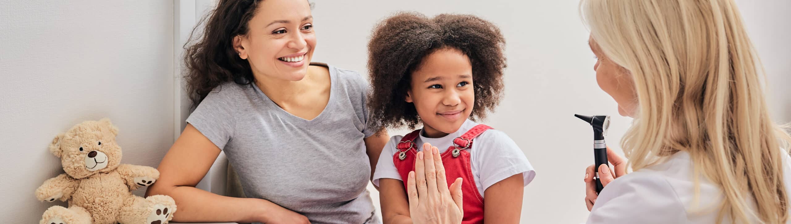 Hearing check-up for a child with an otoscope. Afro-American girl and her mother during a doctor's visit