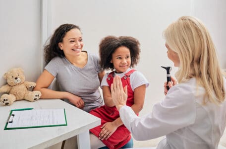 Hearing check-up for a child with an otoscope. Afro-American girl and her mother during a doctor's visit